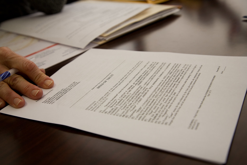 Person reviewing and signing official application documents at a desk